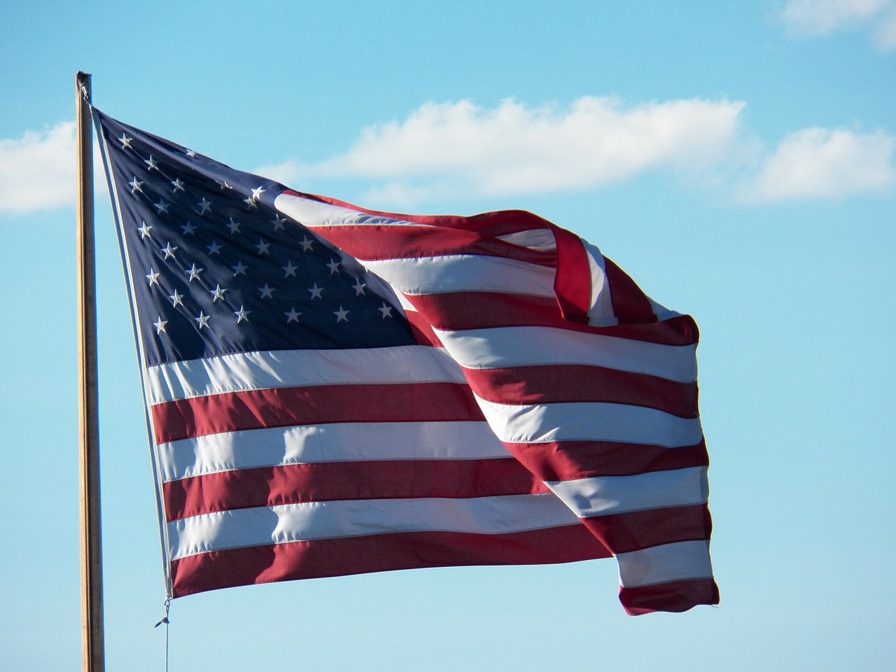 Photo of American Flag waving in the wind on a flagpole